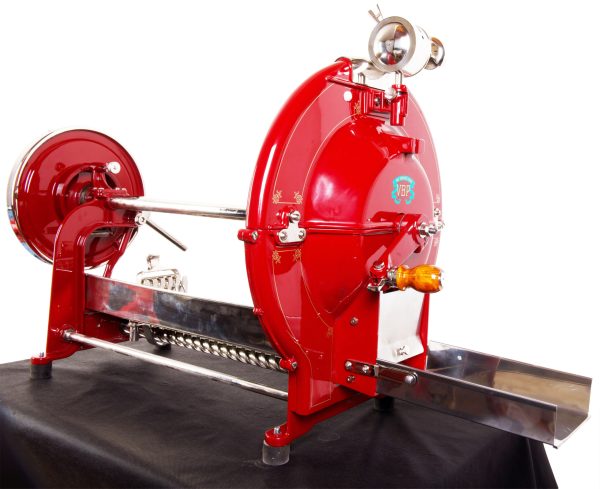Red vintage industrial machine with a large circular flywheel on the left and chrome fittings on a black work surface.